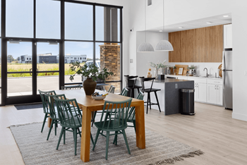 A dining area with a wooden table and chairs and a kitchen with a large window